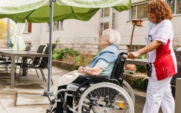 Frau Fuss mit Pflegerin Monique auf der sonnigen Terrasse des «Le Foyer».